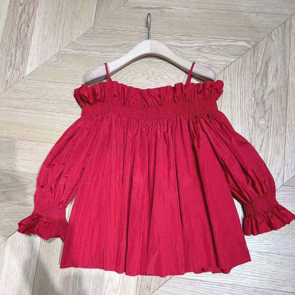 Close-up on smocked off-shoulder detail of Dior red silk taffeta top