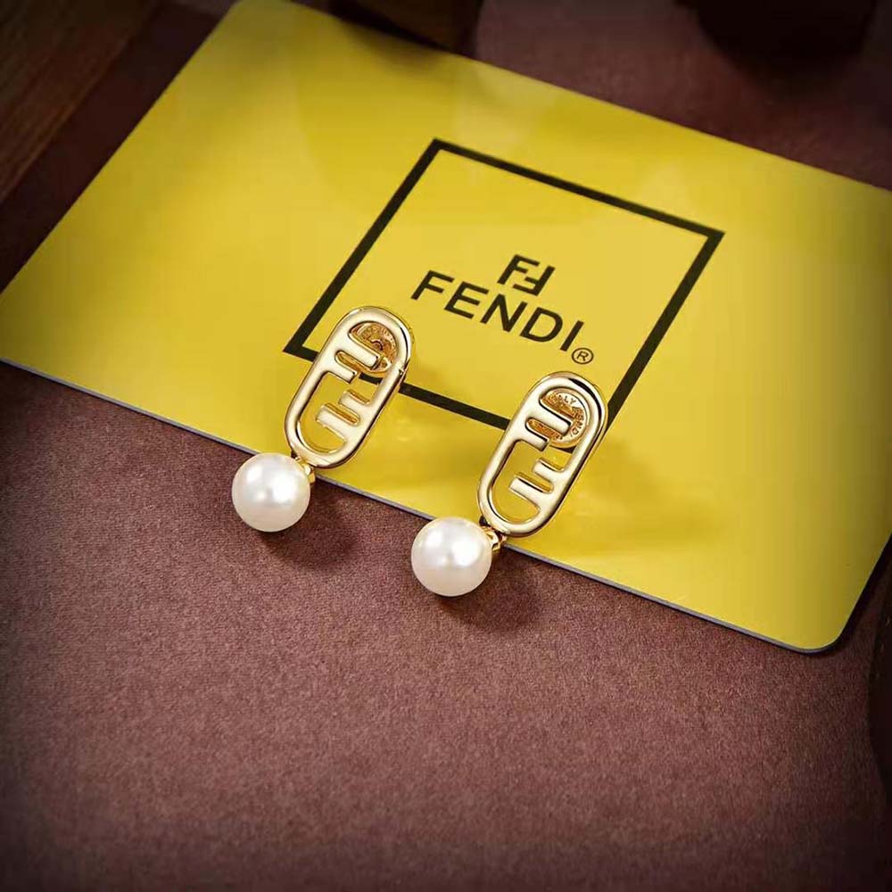 Close-up of signature O’Lock detail on gold-colored Fendi earrings