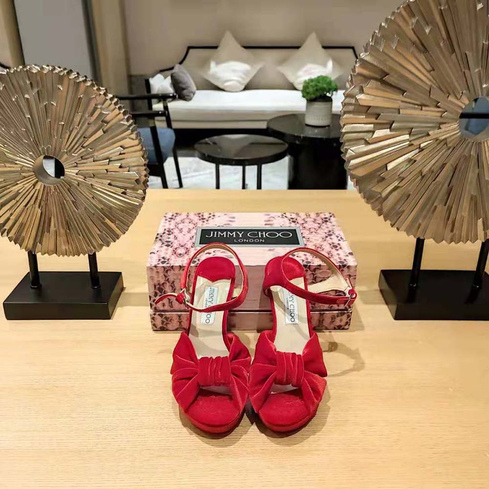 Close-up of gold buckle and red velvet detail on Jimmy Choo sandals