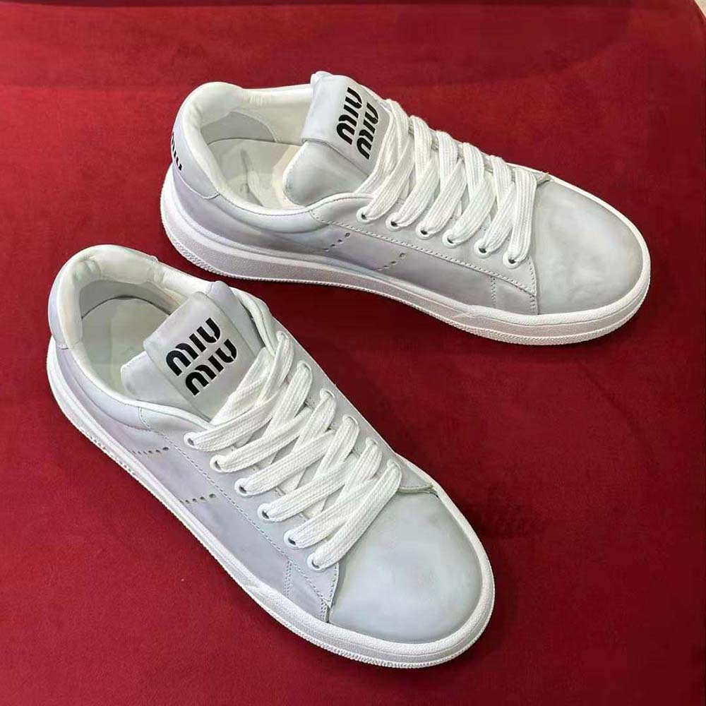 Close-up on silver-tone logo hardware detail on Miu Miu Women Bleached Leather Sneakers-White