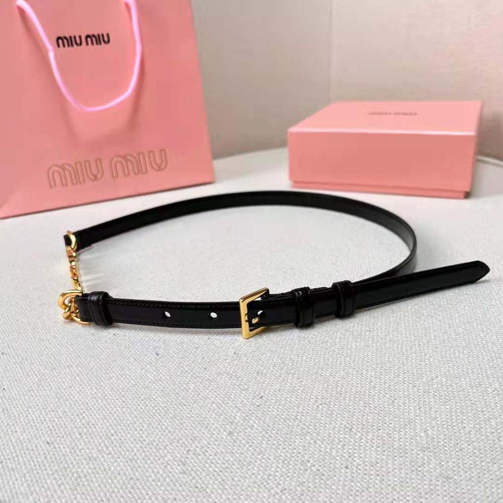 Close-up of polished Miu Miu logo buckle on black leather belt