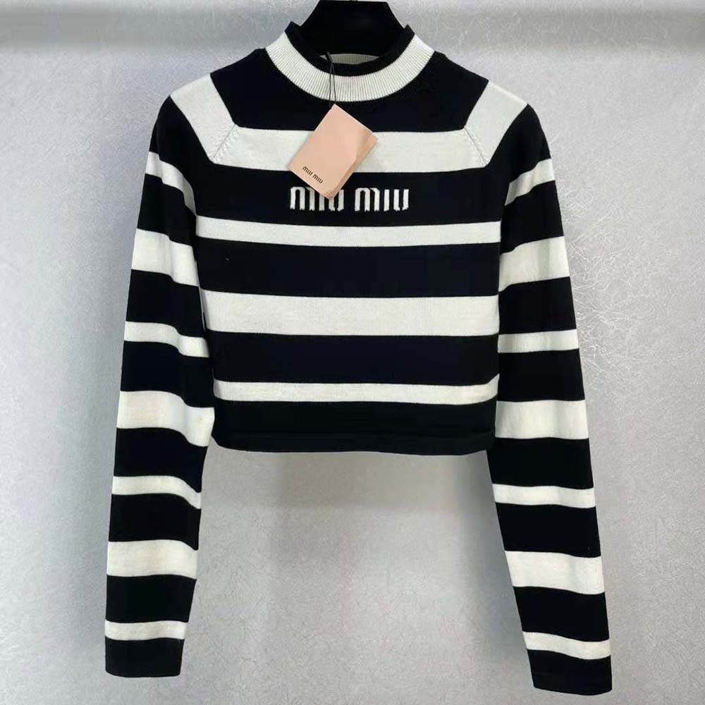 Close-up detailing of Miu Miu logo tab on black cashmere and silk turtleneck