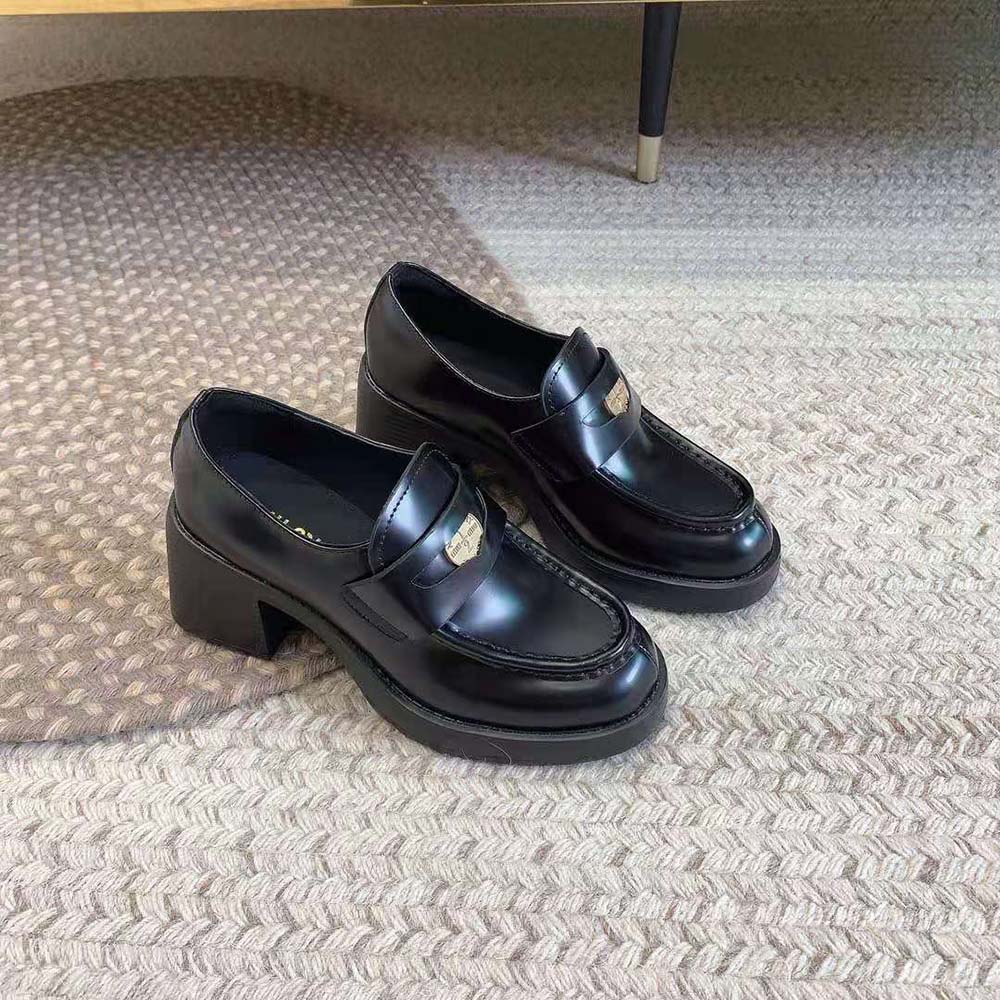 Close-up of black leather and embossed metal detail on Miu Miu loafers