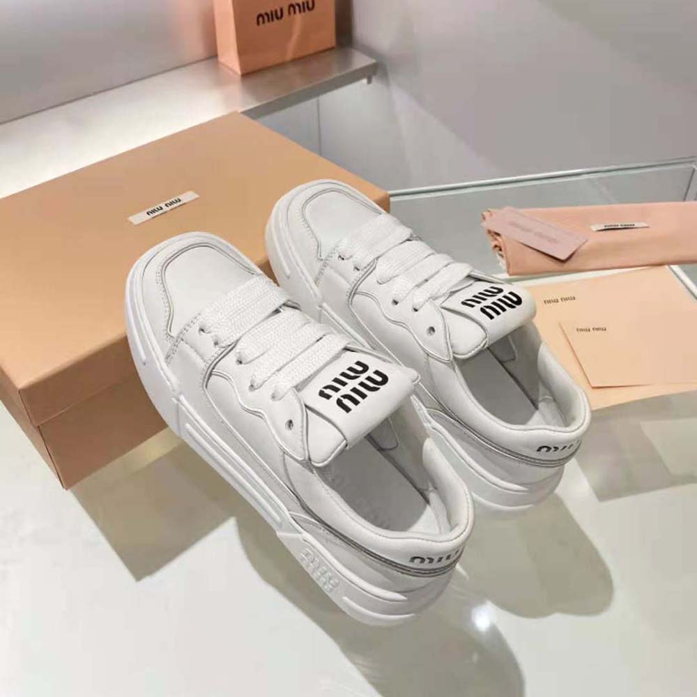 Rear view highlighting embossed Miu Miu logo on heel of white sneakers