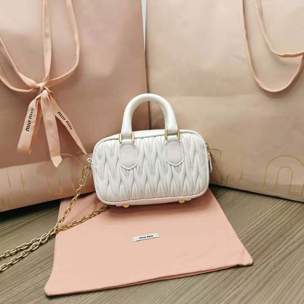 Side angle showing gold hardware on Miu Miu white top-handle mini-bag