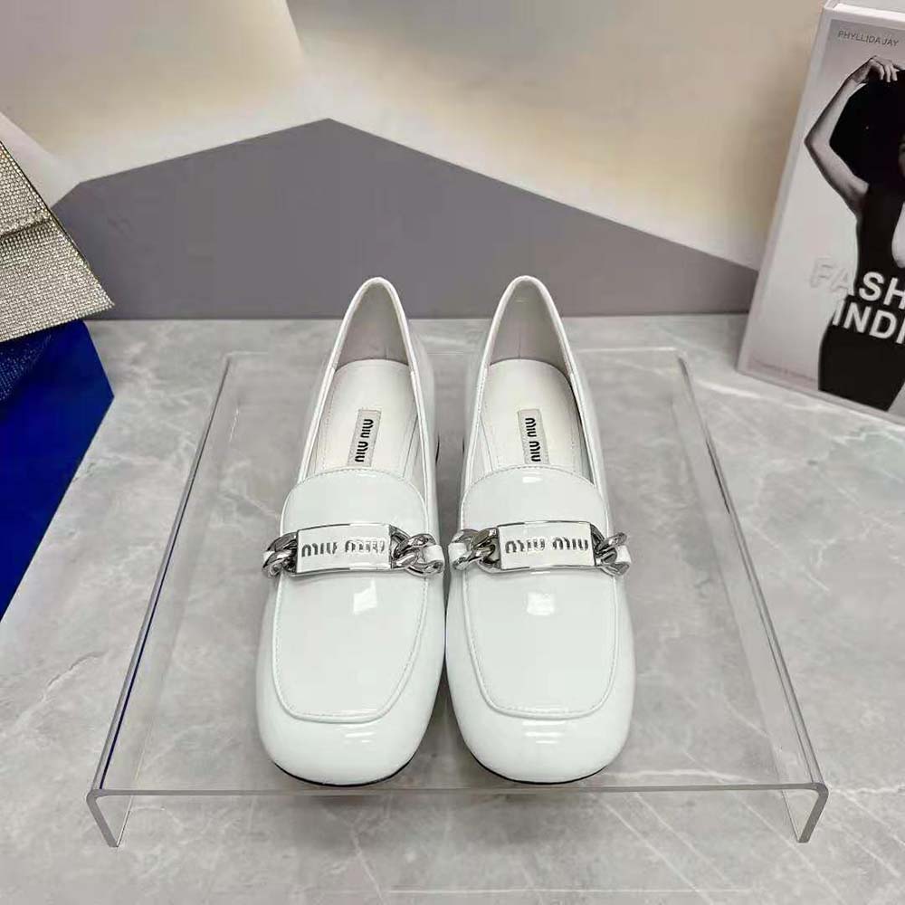 Close-up on glossy patent leather and Miu Miu hardware detail on white loafer