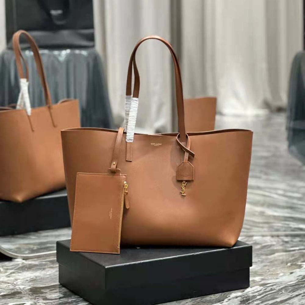 Close-up of gold YSL logo hardware on brown leather bag