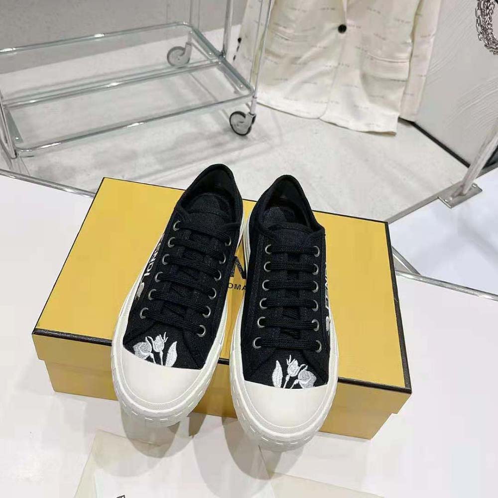 Close-up of gold Fendi logo hardware on black canvas low tops