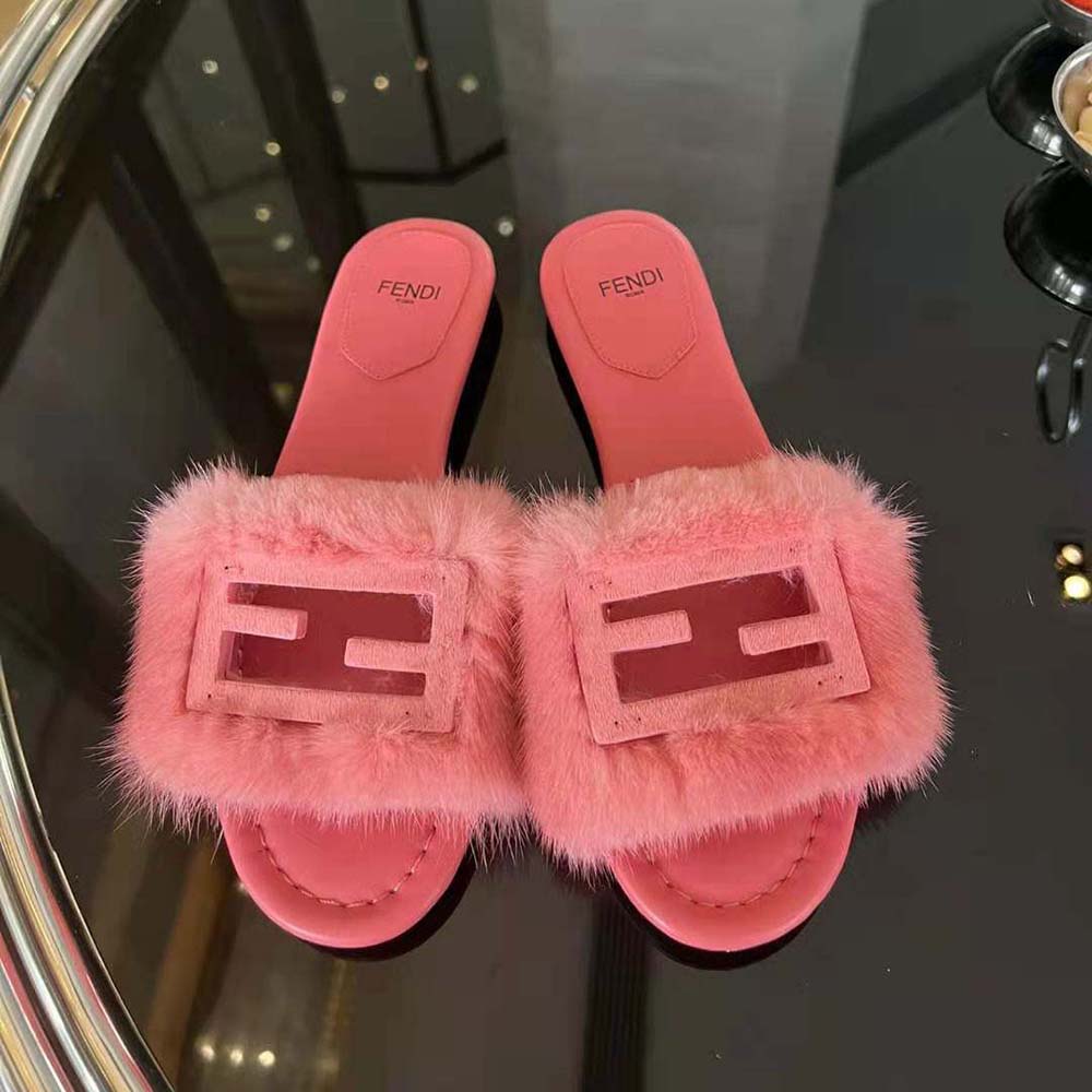 Close-up on gold-tone Fendi hardware detail on pink mink slides