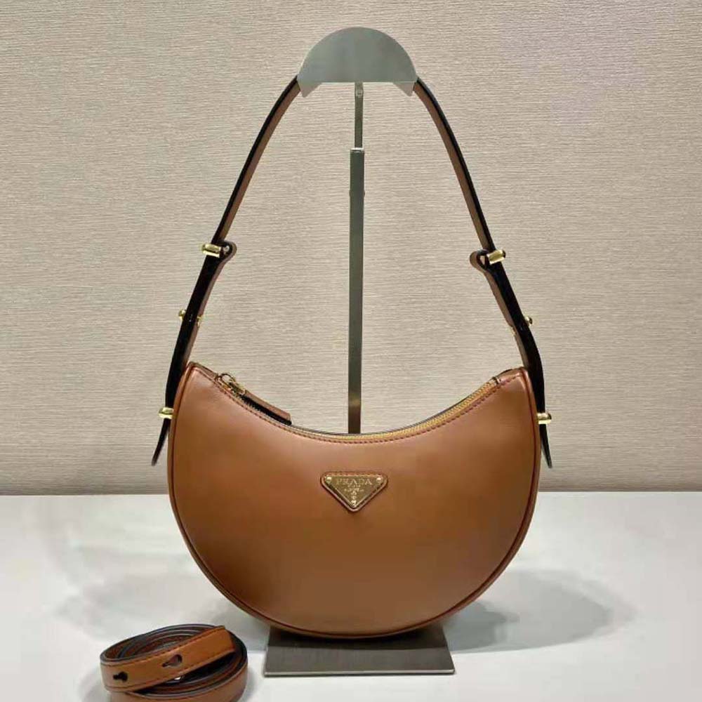 Close-up of enameled metal triangle logo on Prada brown shoulder bag