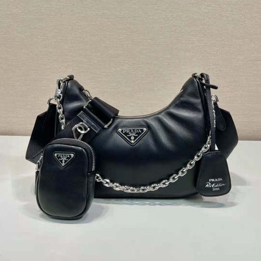 Close-up of silver-tone Prada logo on black padded leather shoulder bag