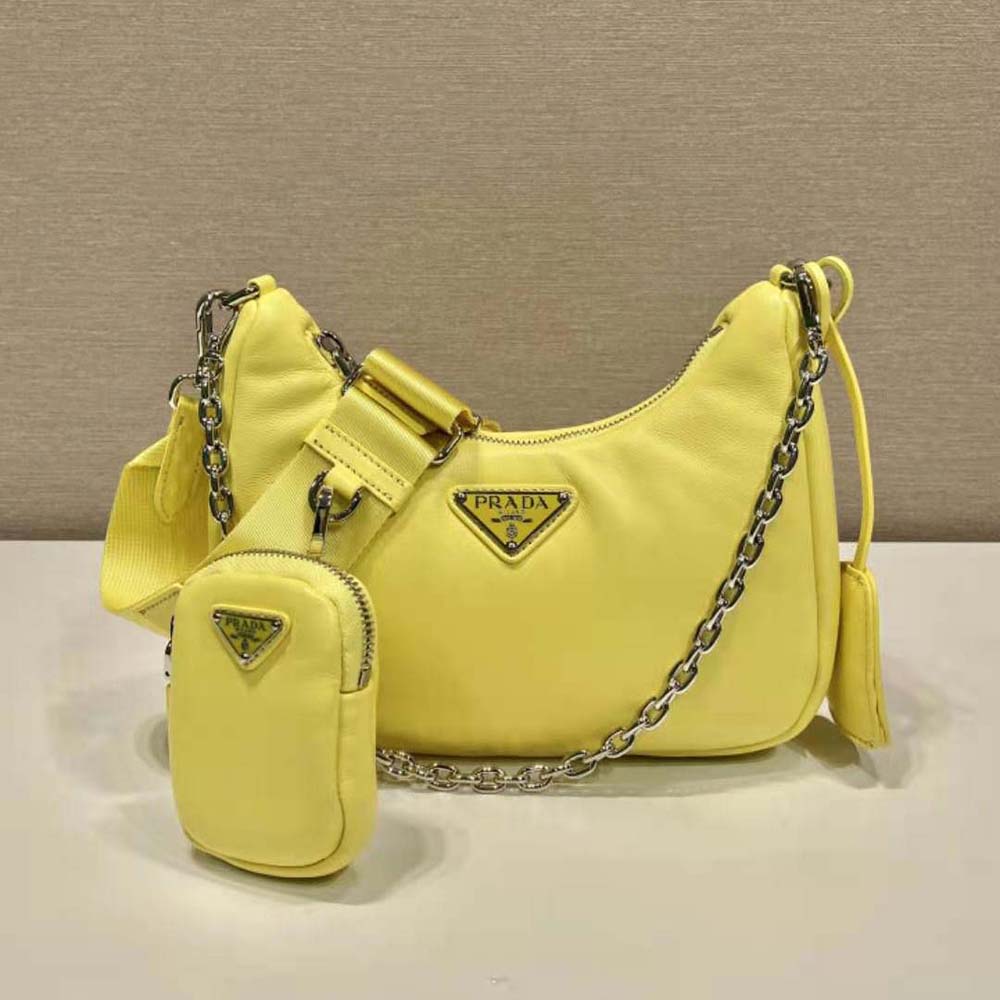 Close-up detail of silver Prada logo on yellow leather shoulder bag