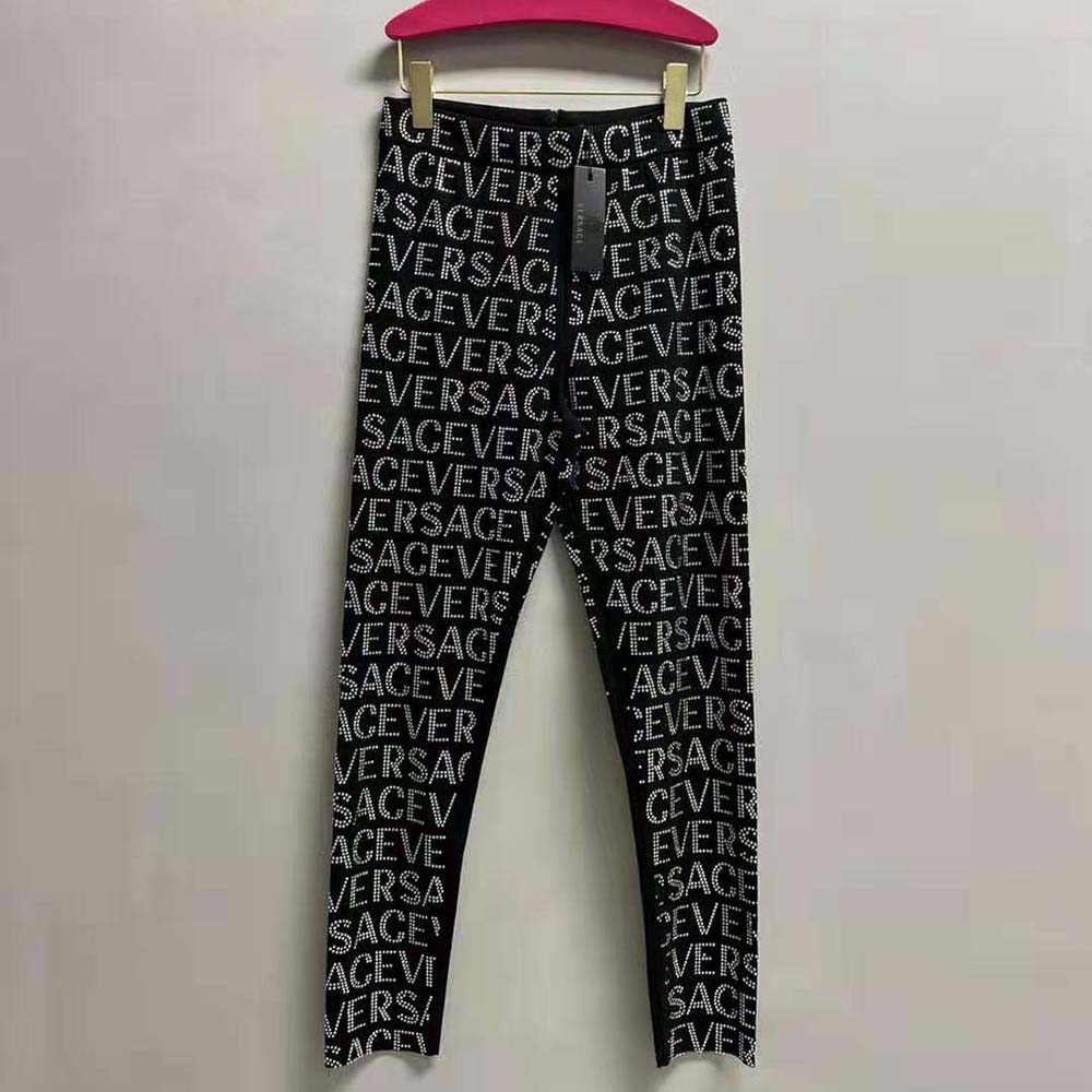 Close-up of crystal-embellished Versace logo on black leggings