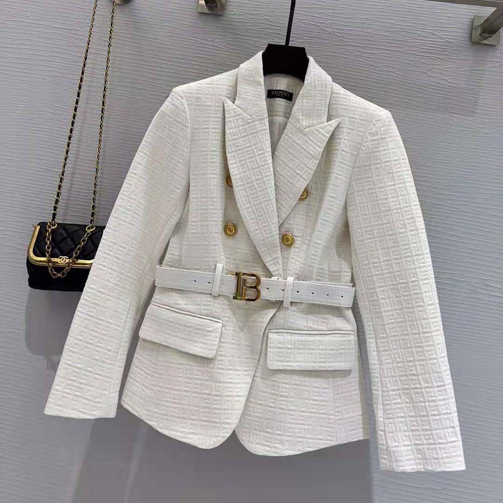 Close-up of signature Balmain buckle on white cotton blazer