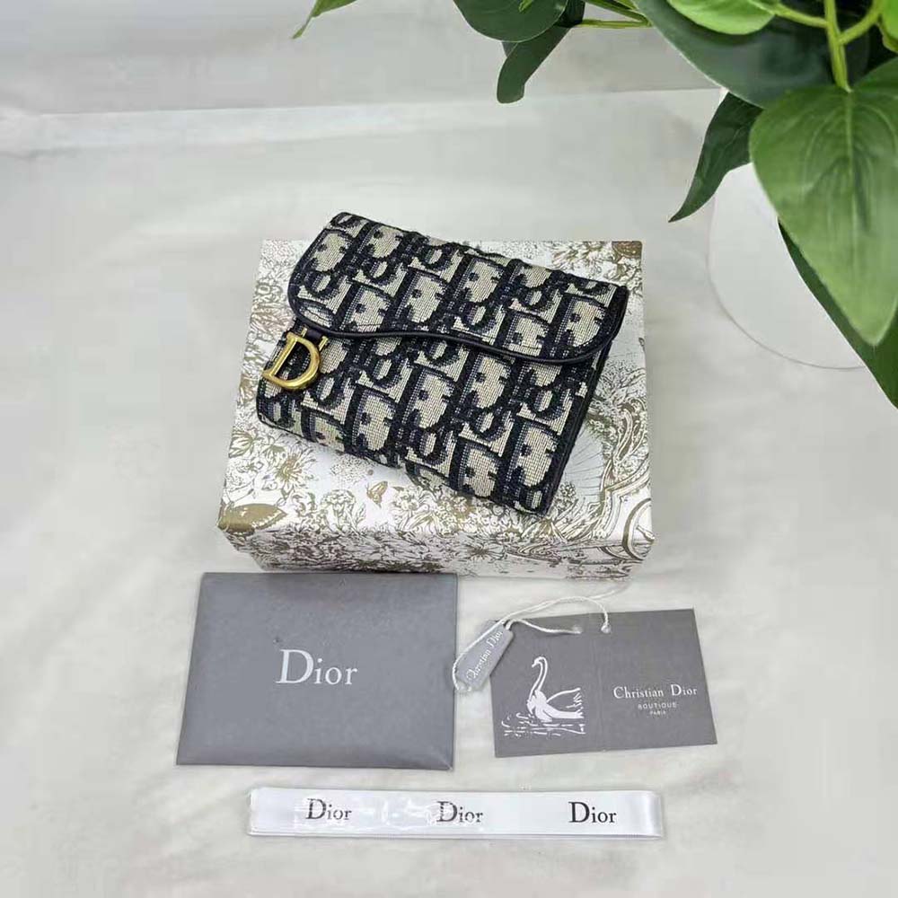 Close-up detail of blue jacquard fabric and gold hardware on Dior wallet