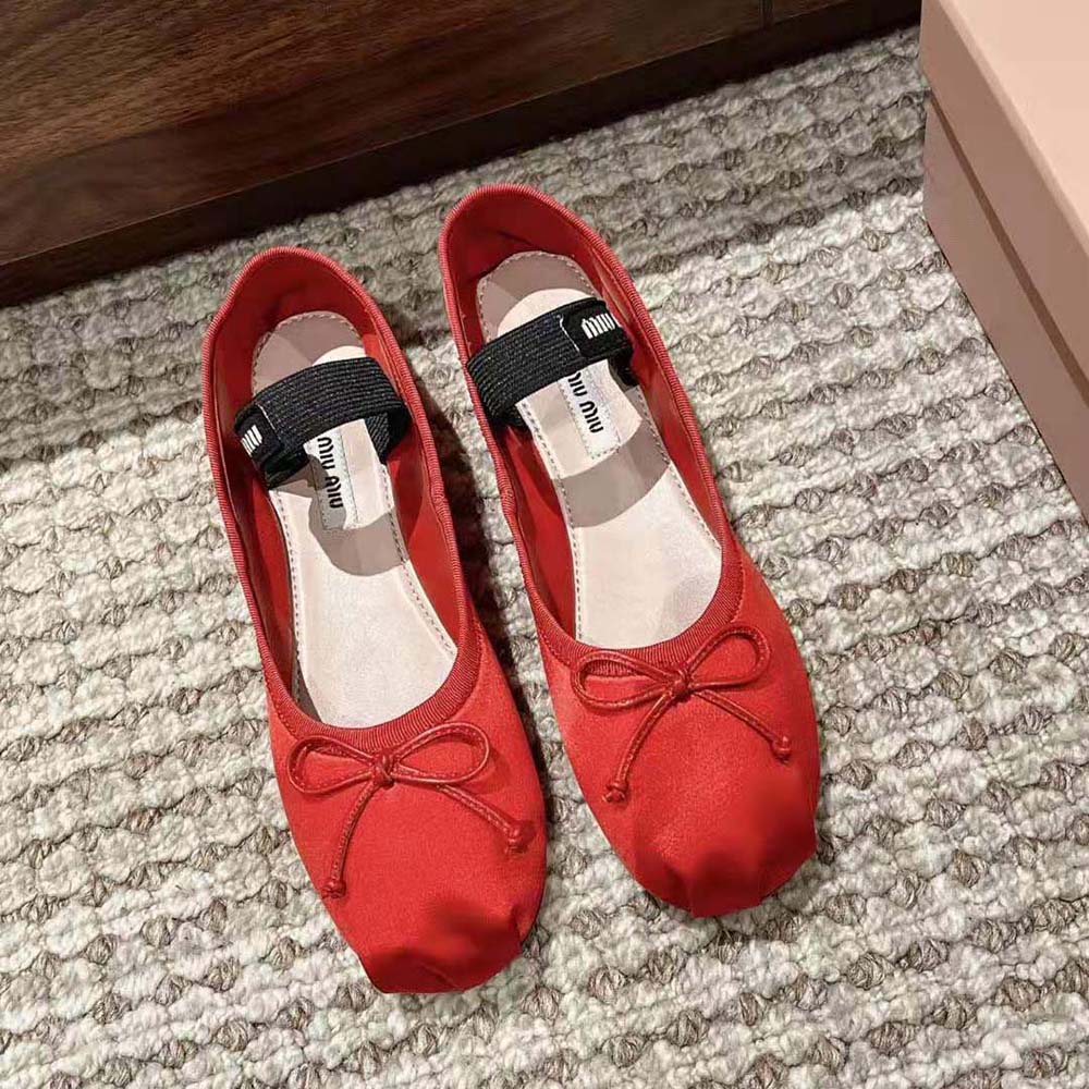Close-up detail of knit logo label on red satin Miu Miu ballerinas
