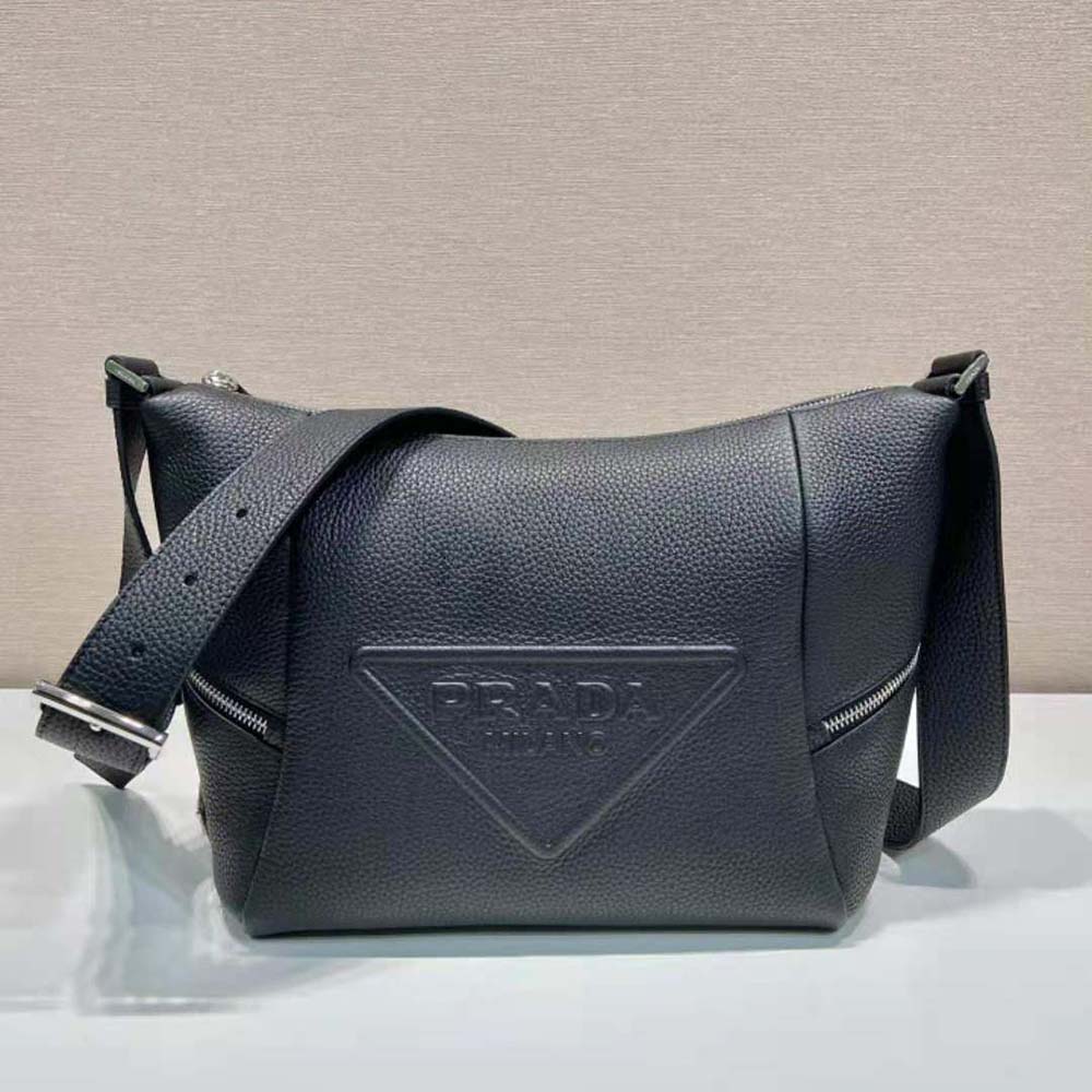 Close-up on gunmetal Prada logo hardware on black leather bag