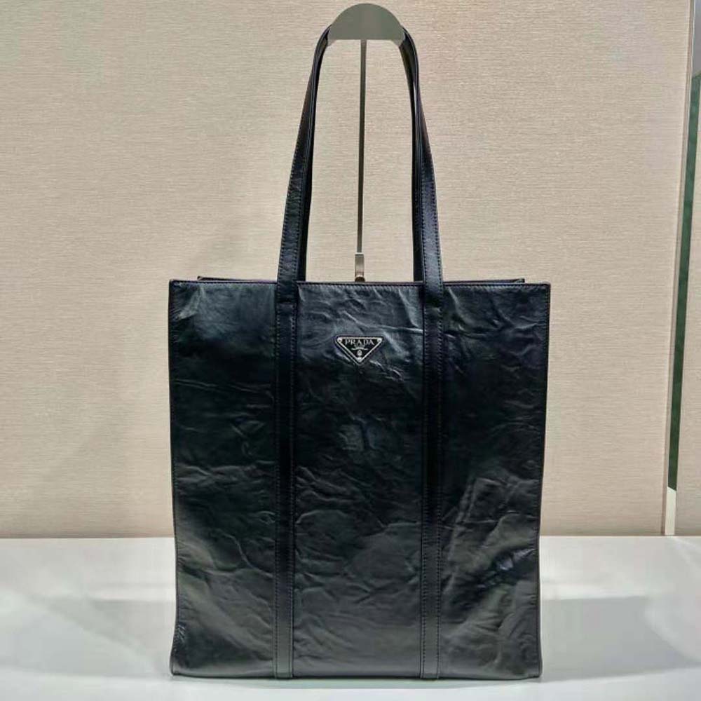 Side angle showing structured silhouette of Prada Women Medium Antiqued Nappa Leather Tote Bag-Black