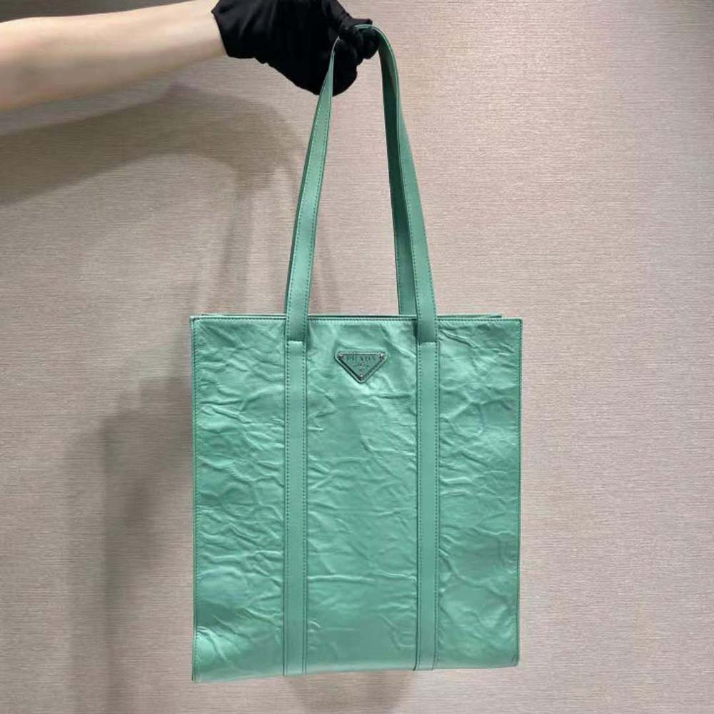 Close-up on gold-tone hardware and zip of Prada green leather tote