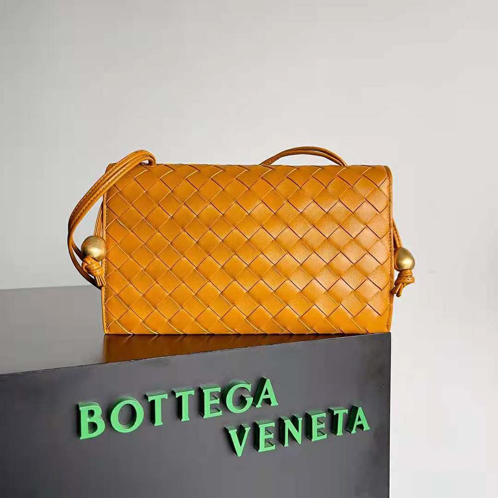 Side view showing gold-tone hardware and strap of Bottega Veneta orange pouch