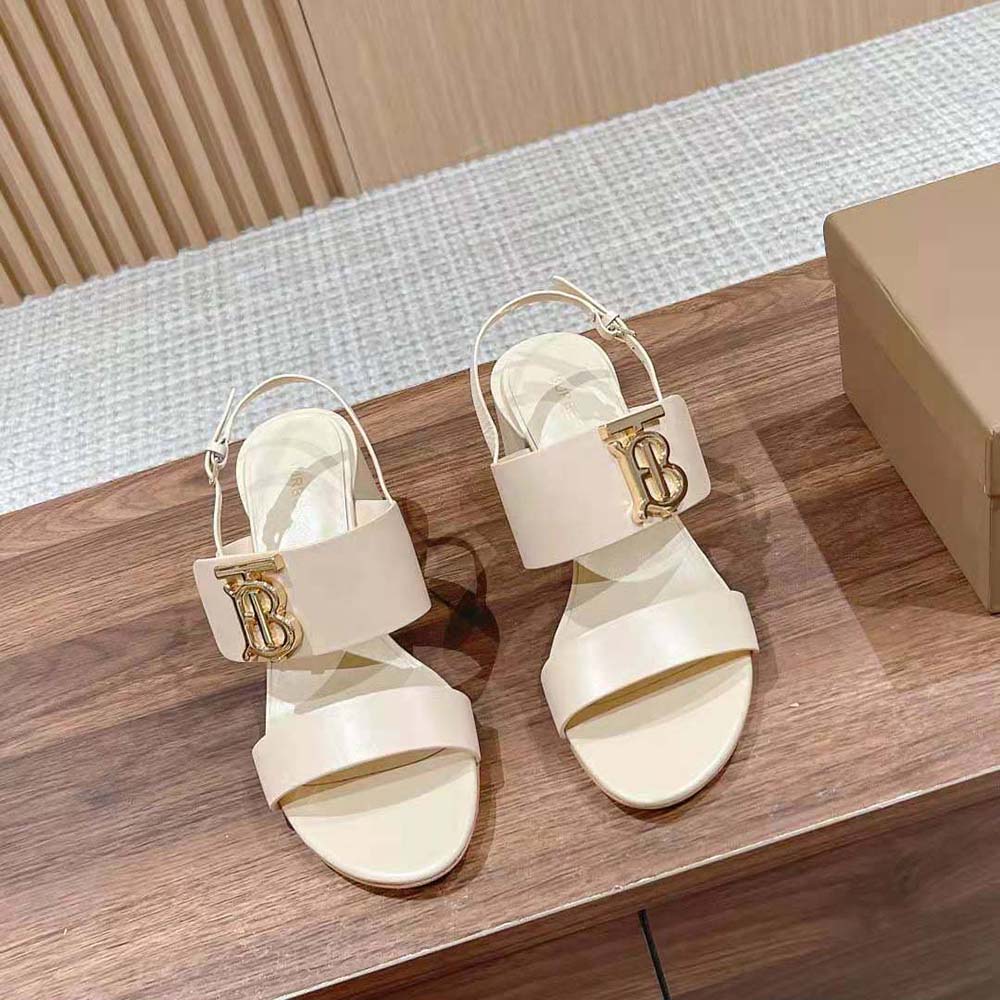 Close-up of white leather and Burberry monogram hardware detail on sandal