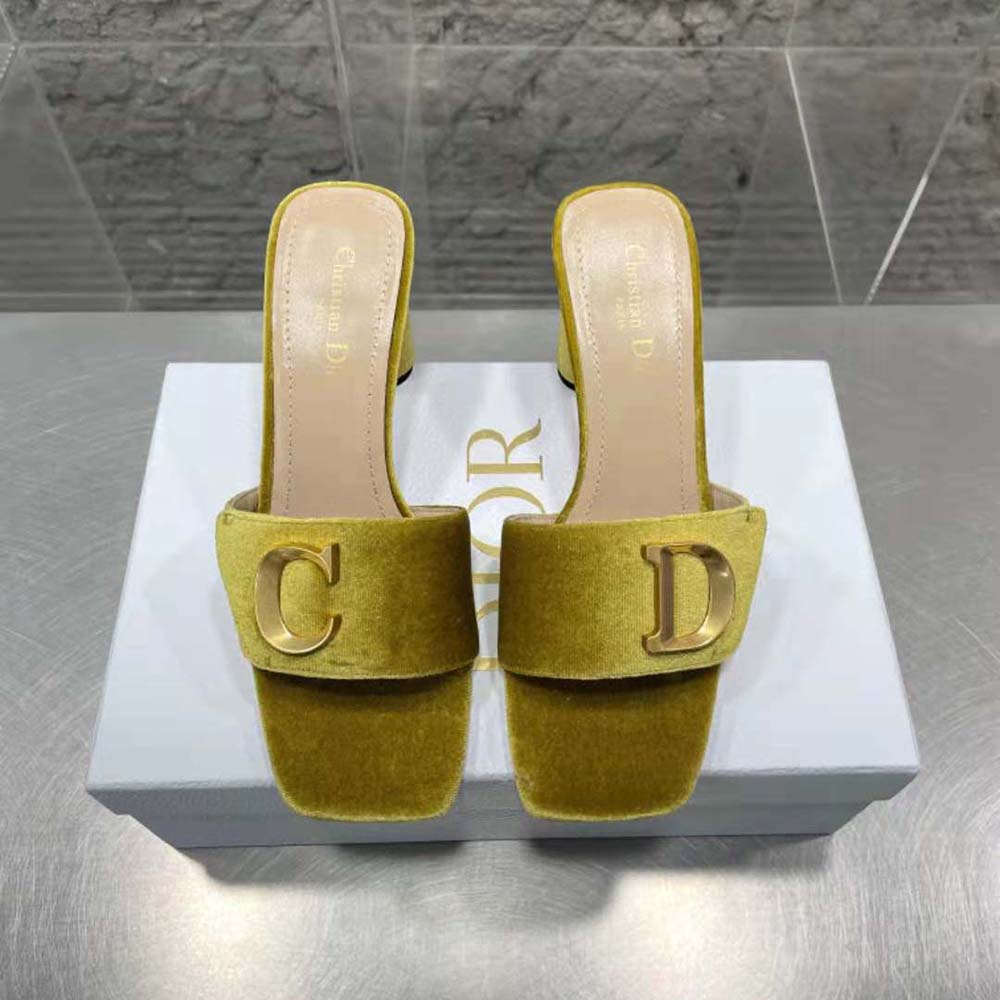 Close-up on Dior metal logo detail on yellow velvet slide