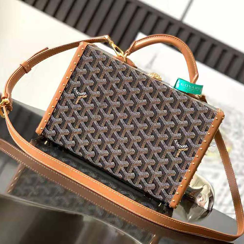 Close-up of textured Goyardine canvas and brass hardware on Sac Malle Grand Hôtel