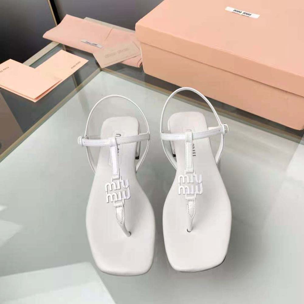 Close-up of white patent leather and metal logo on Miu Miu thong sandal