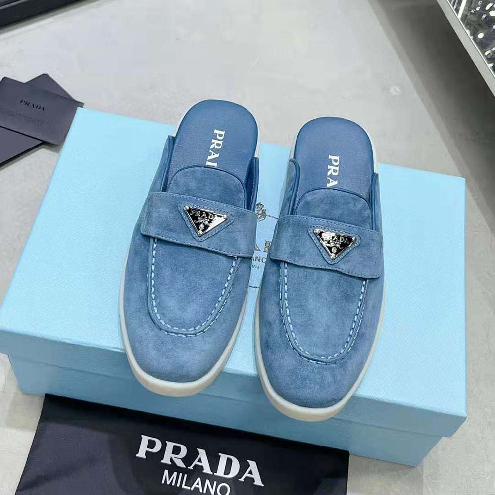 Close-up of enameled metal triangle logo on Prada Men Suede Sabots blue suede