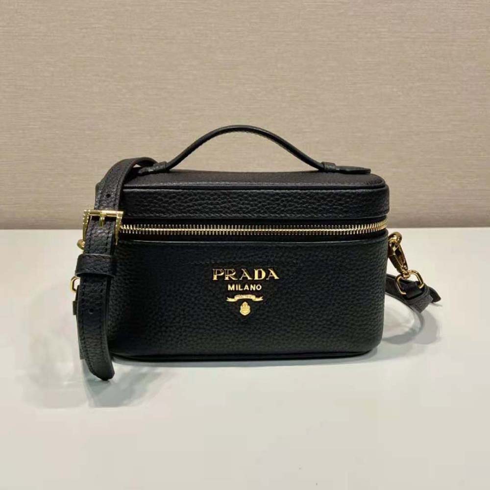 Close-up detail of black leather texture and gold hardware on Prada bag