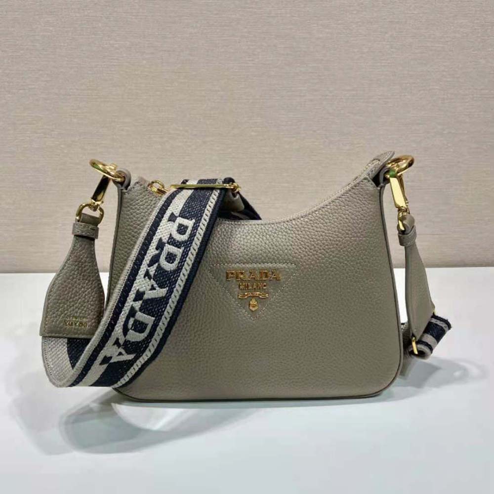 Close-up of silver Prada logo hardware on gray leather shoulder bag
