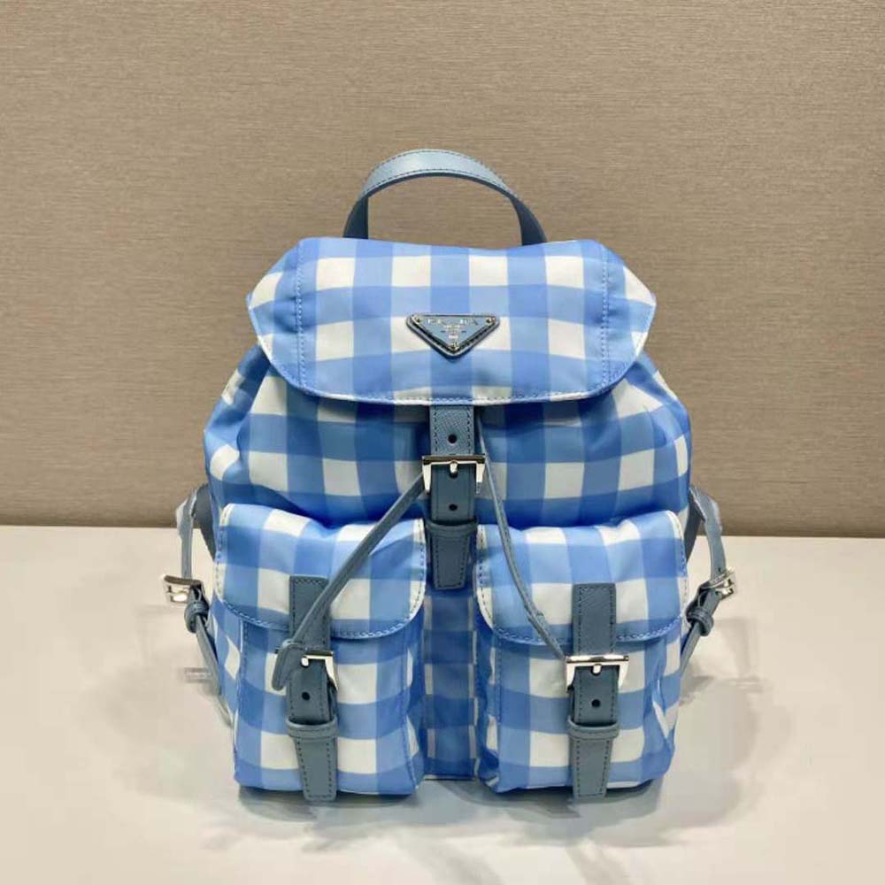 Close-up on silver Prada logo hardware on blue printed backpack