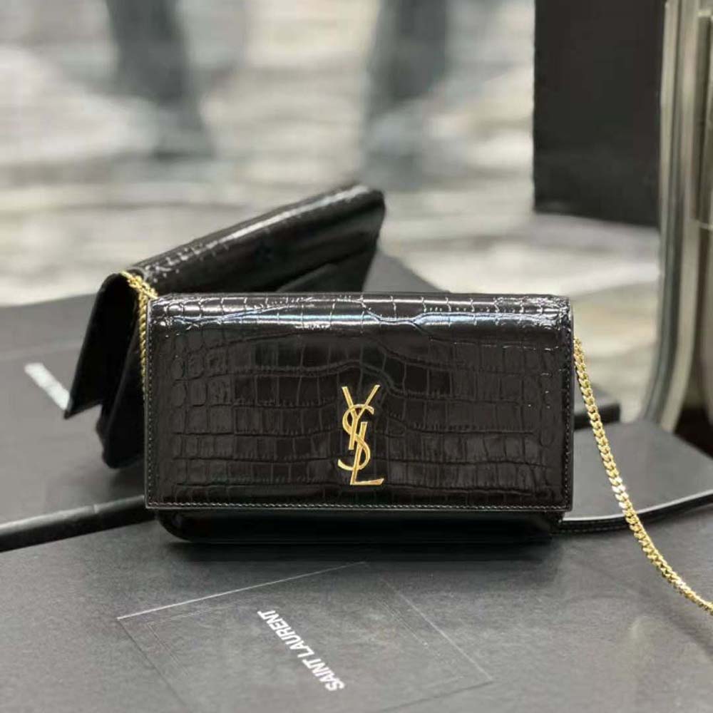 Close-up of gold YSL logo hardware on shiny crocodile-embossed leather