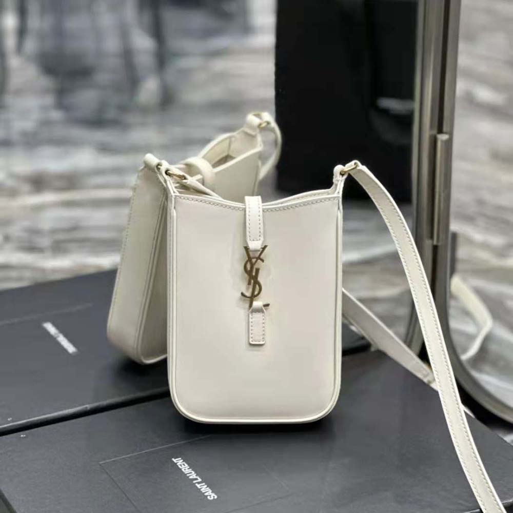 Close-up of gold YSL logo and magnetic flap on white leather mini bag