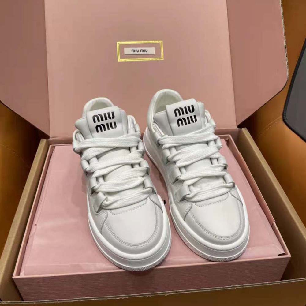 Close-up of bold lettering logo on white leather Miu Miu sneakers