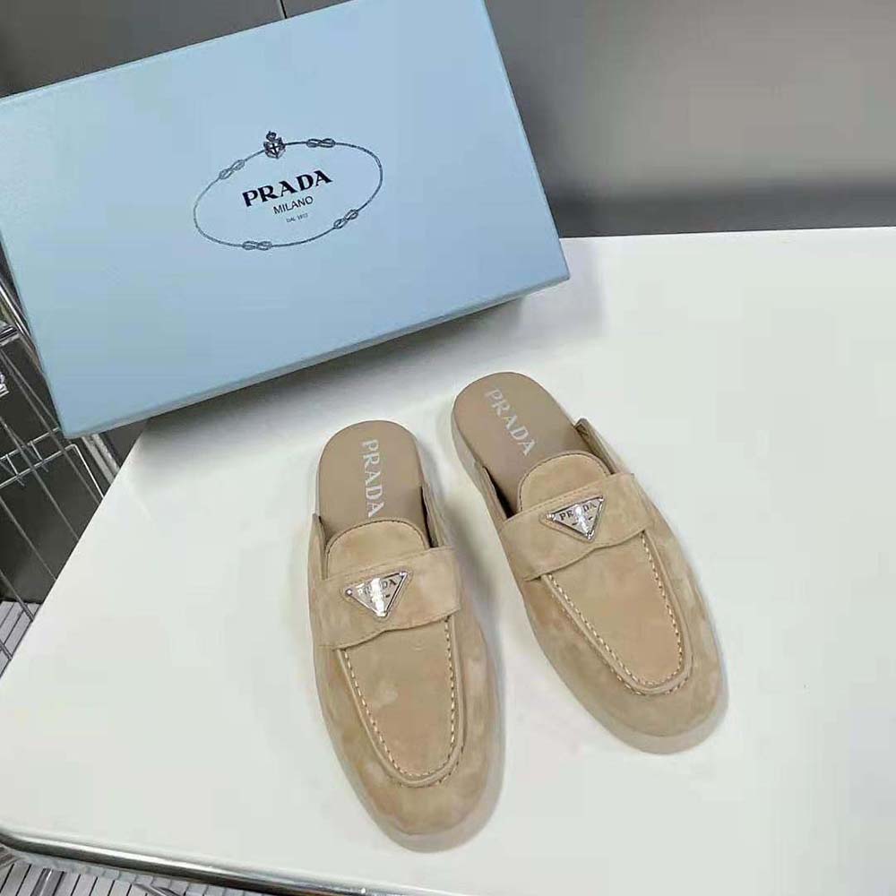 Close-up of signature enameled metal triangle logo on Prada brown suede sabots