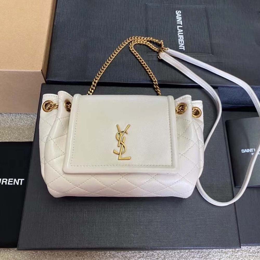 Close-up of gold YSL monogram hardware on white lame leather bag