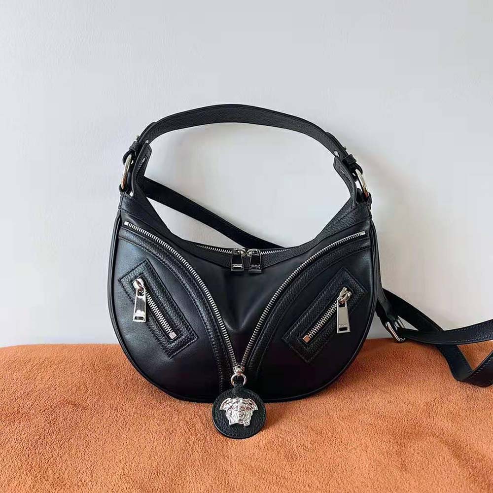 Close-up of gold-tone Versace logo hardware on black hobo bag
