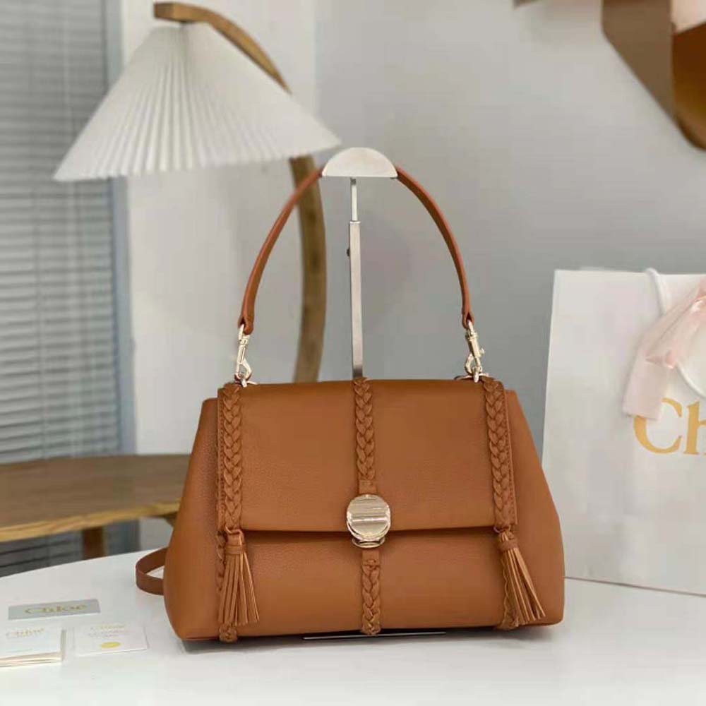 Close-up of gold hardware and brown leather texture on Penelope shoulder bag