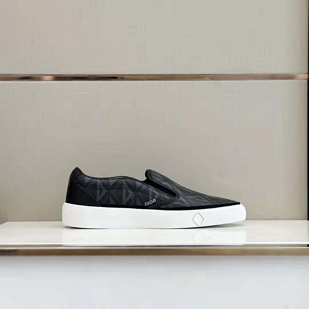 Close-up of silver Dior hardware on slip-on sneaker’s black canvas upper
