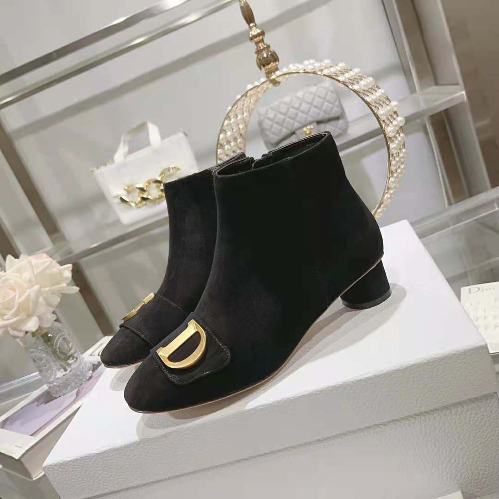 Close-up of Dior signature silver-tone heel on black suede ankle boot