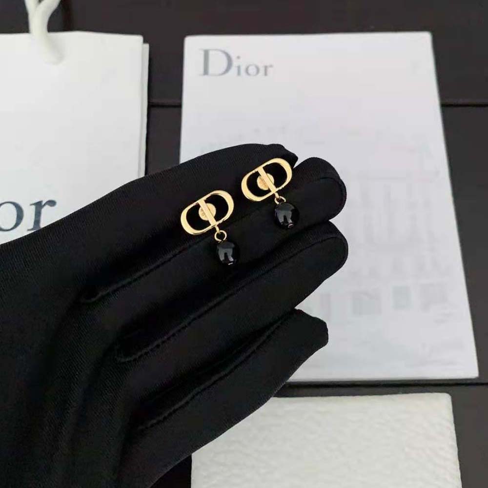 Close-up of black resin pearls and gold-finish metal on Dior Women Petit CD Earrings