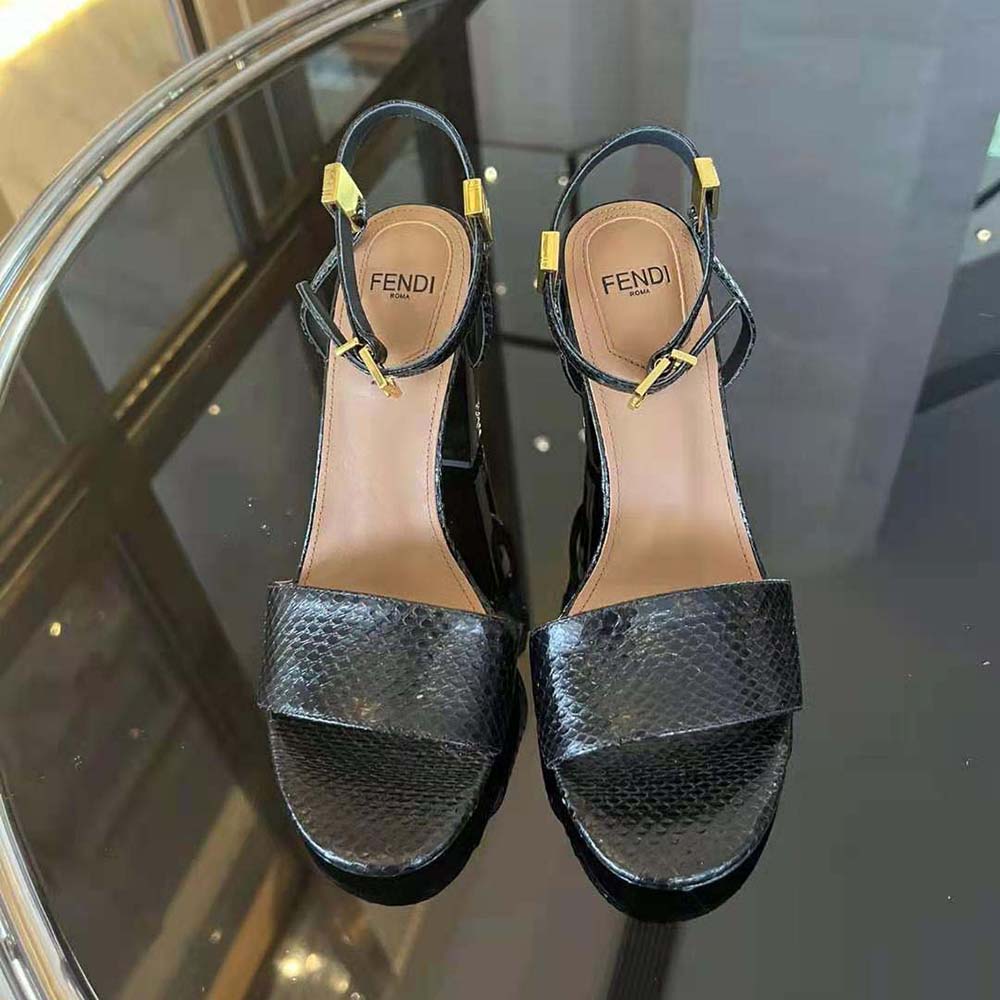 Close-up on gold Fendi logo hardware on black karung leather sandals