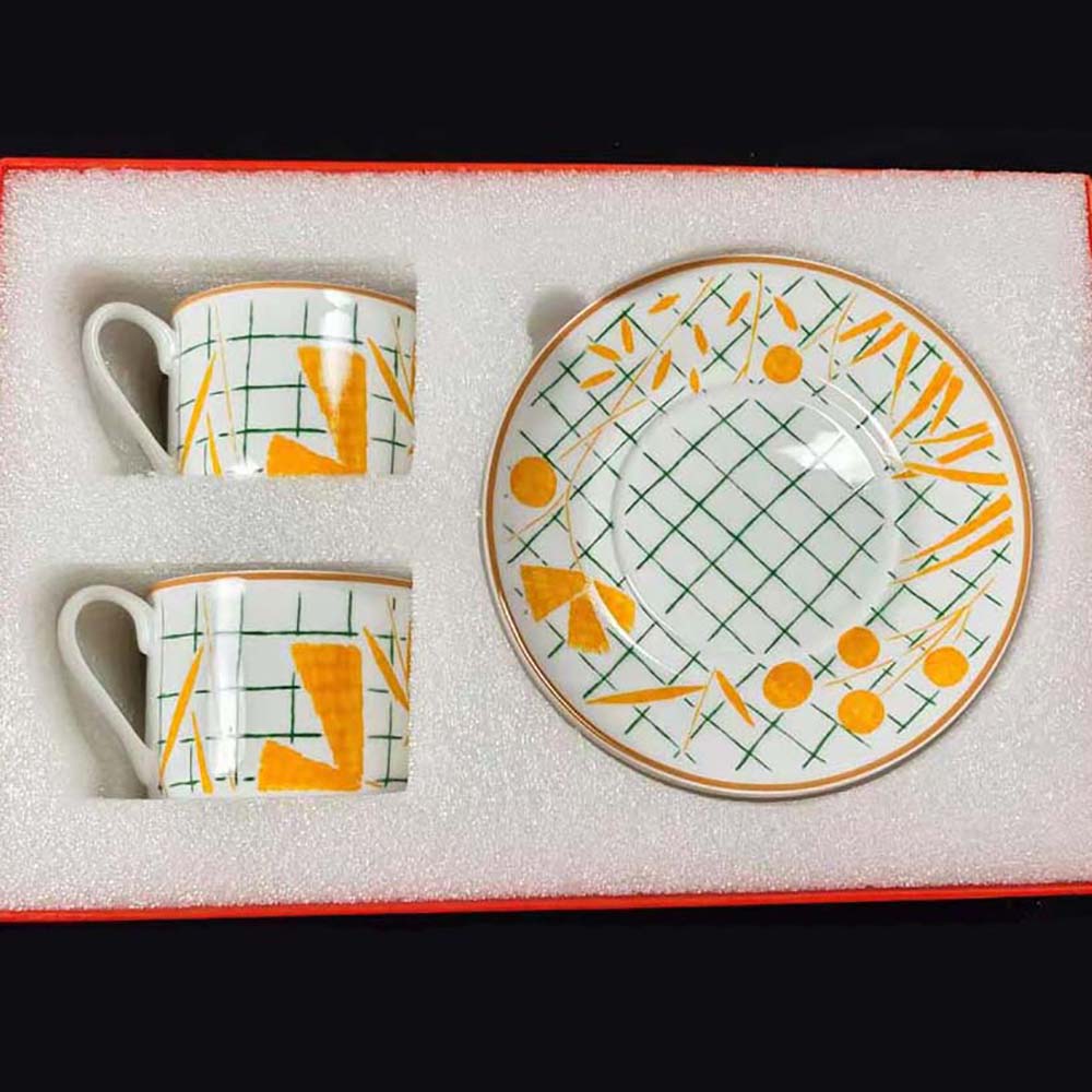 Close-up on yellow garden motif and gold trim details on Hermes tea cup