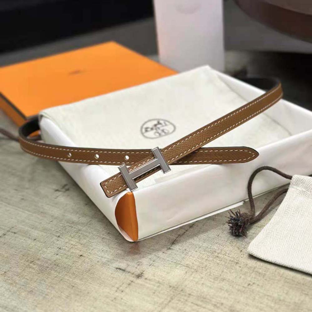 Close-up on silver Hermes 'H' buckle of reversible leather strap belt