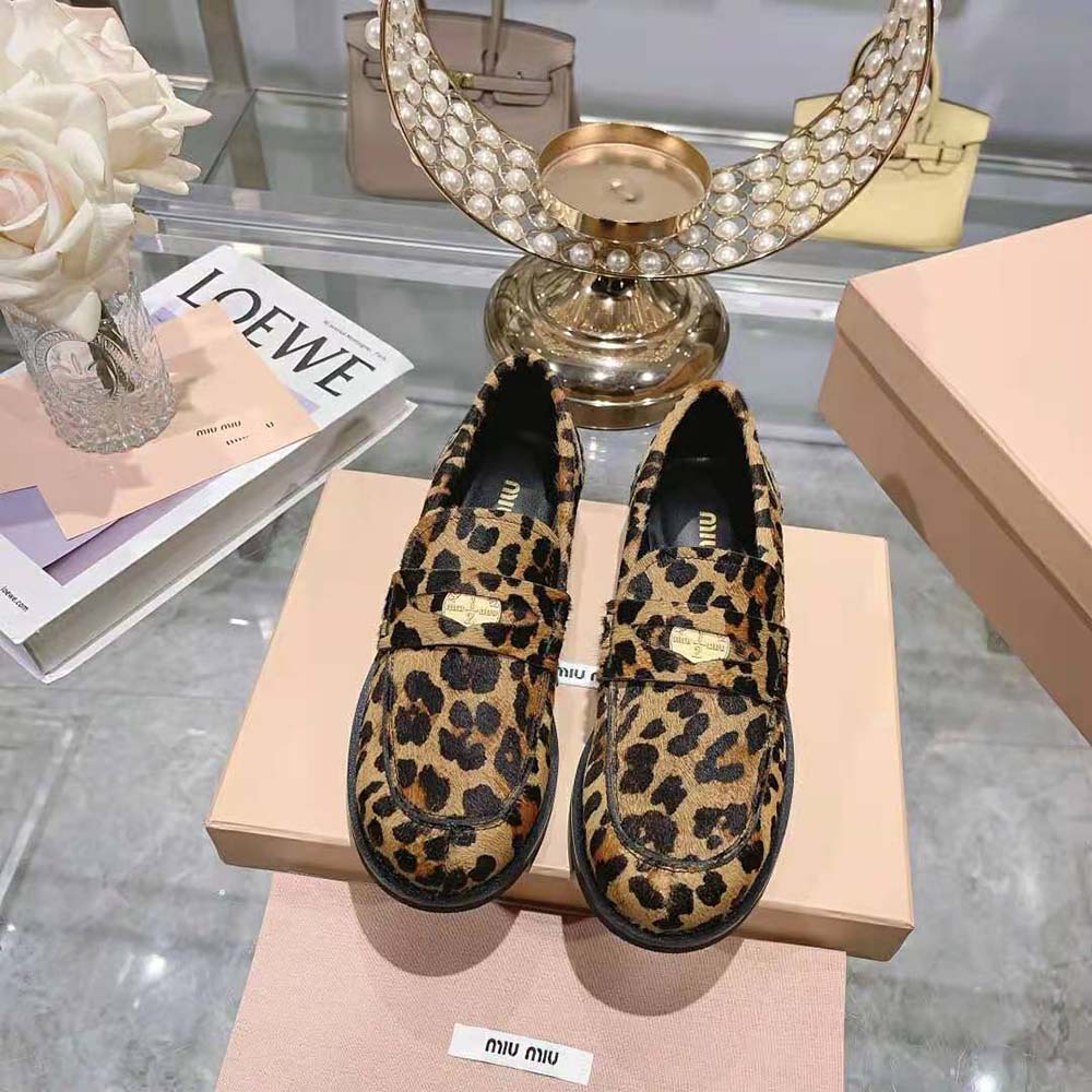 Close-up on gold-tone hardware of Miu Miu leopard-print loafers
