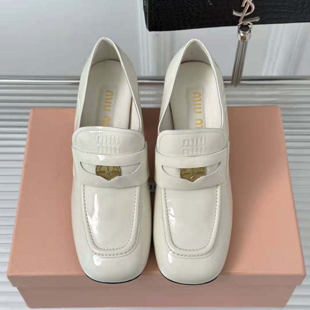 Close-up of embossed logo detail on tongue of Miu Miu white patent leather loafers