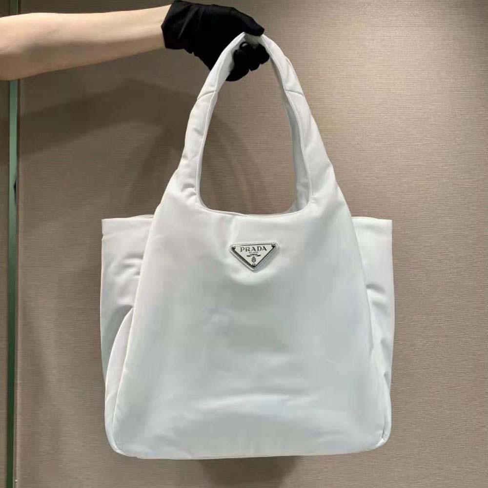 Close-up of silver Prada logo hardware on padded white nylon tote