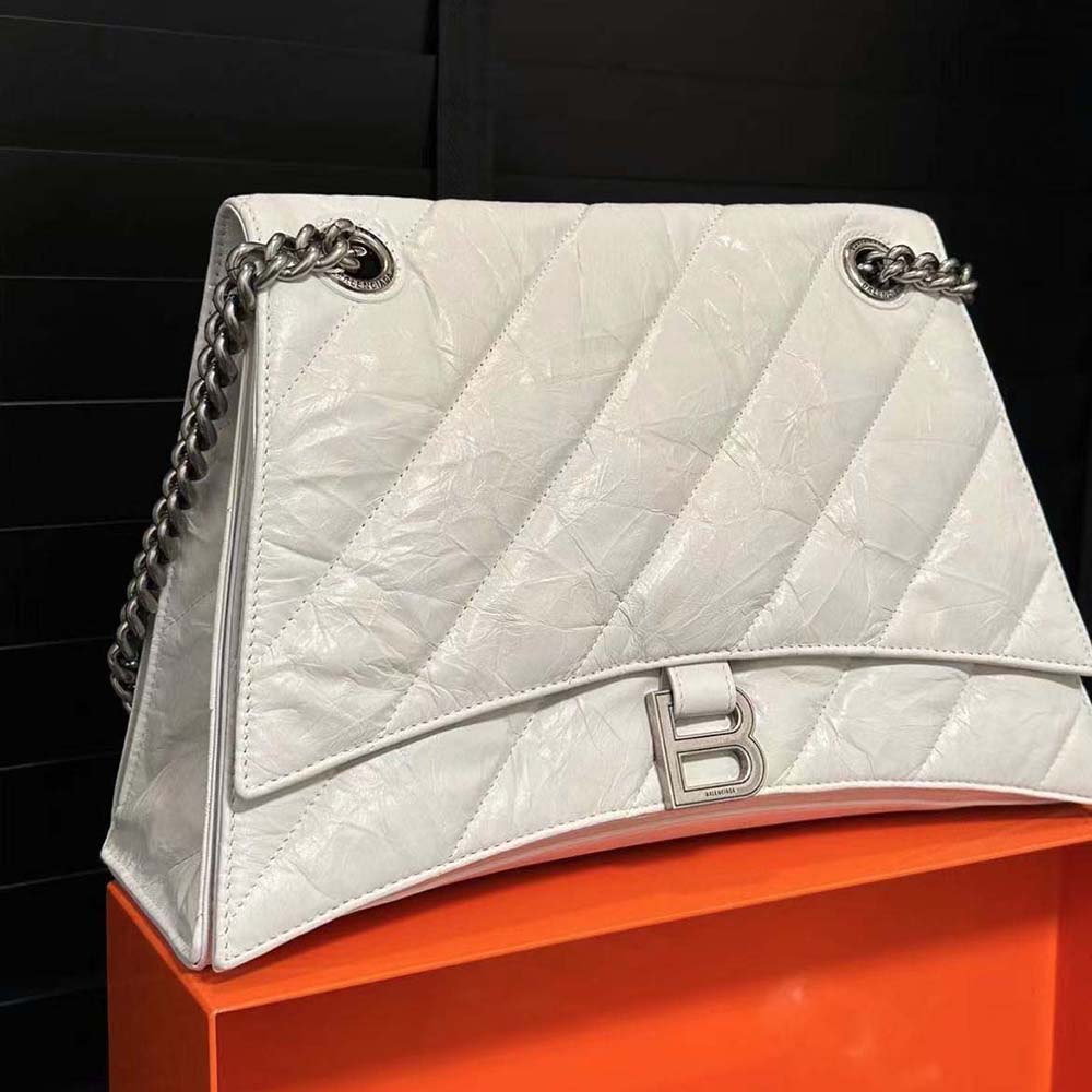 Close-up of white quilted leather and silver chain detail on bag