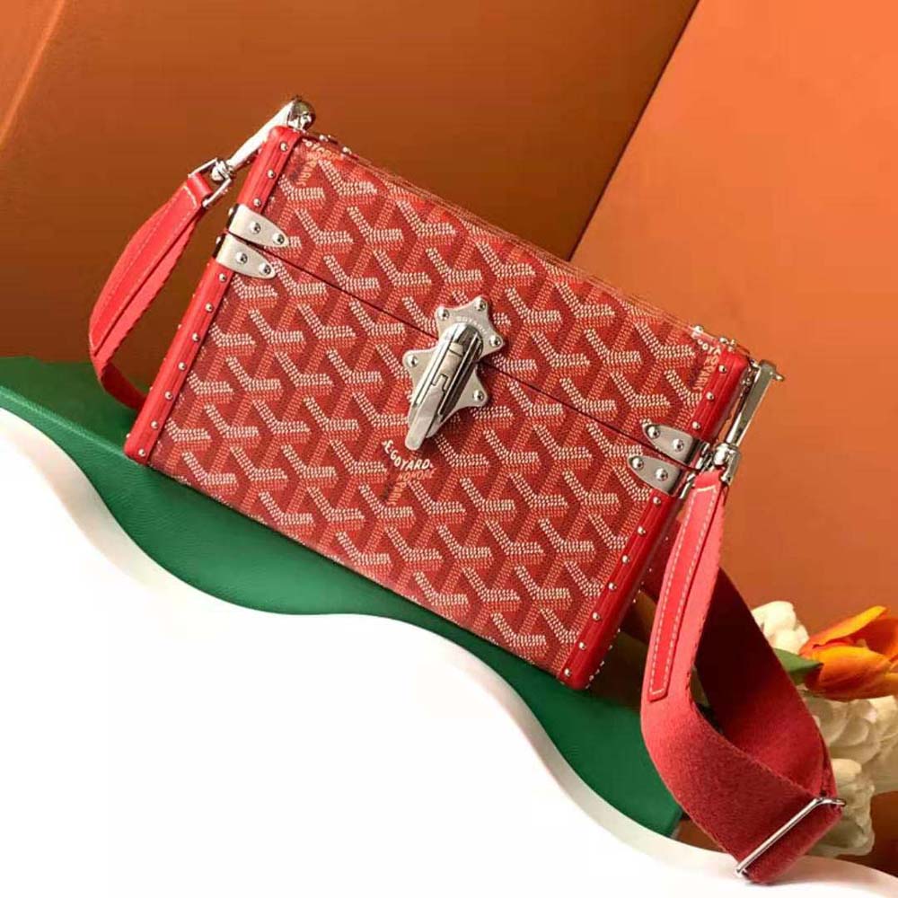 Close-up of gold hardware and red Clamecy cowhide on Goyard Cassette Trunk Bag